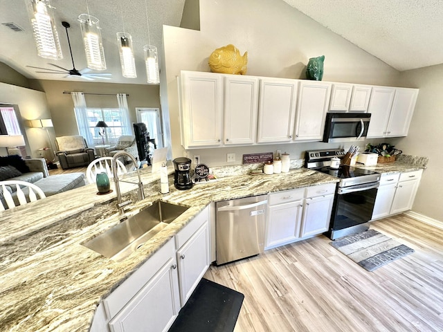 kitchen featuring stainless steel appliances, lofted ceiling, white cabinetry, and sink