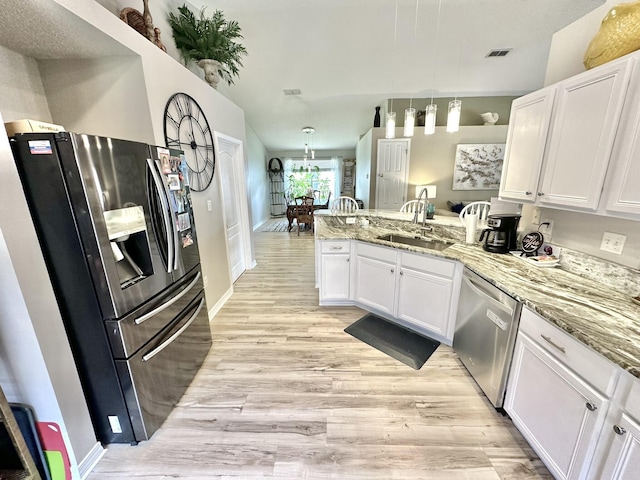 kitchen featuring stainless steel appliances, light stone countertops, kitchen peninsula, white cabinets, and sink