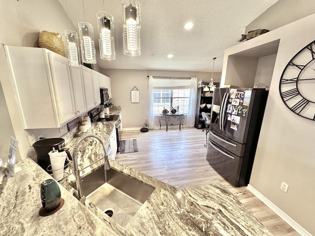 kitchen featuring sink, decorative light fixtures, light stone counters, refrigerator with ice dispenser, and black range with electric cooktop