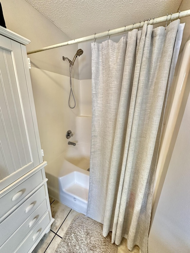 bathroom with a textured ceiling, shower / bath combination with curtain, and tile patterned flooring