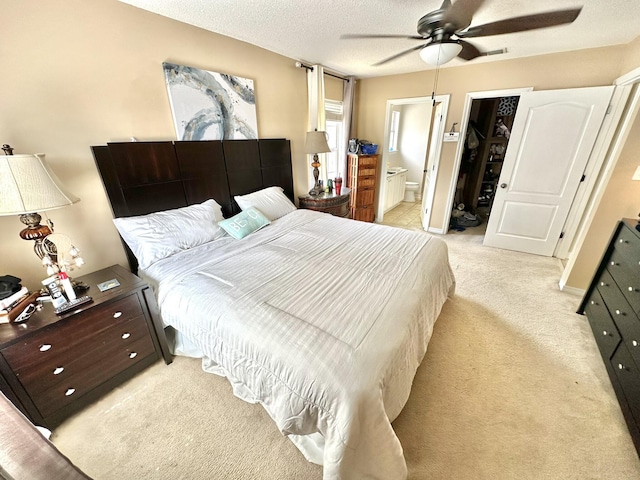 carpeted bedroom with a textured ceiling, ceiling fan, and connected bathroom