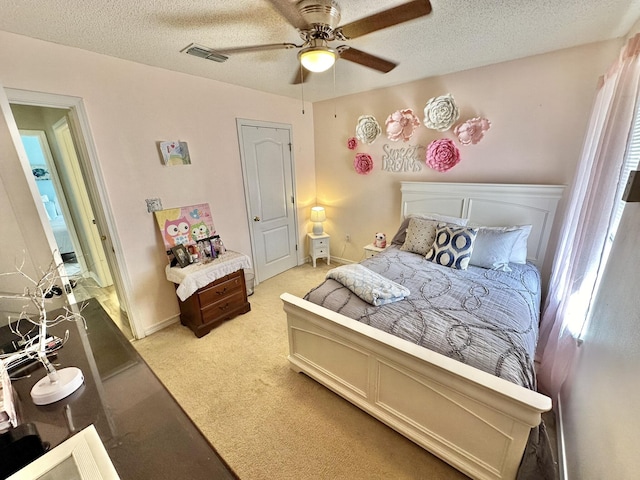 bedroom featuring ceiling fan, light carpet, and a textured ceiling