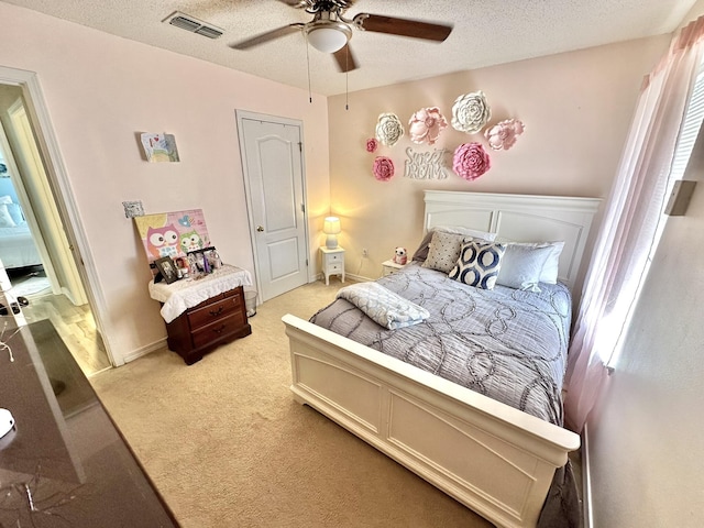 bedroom featuring a textured ceiling, ceiling fan, and light colored carpet