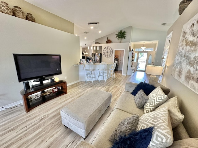 living room featuring high vaulted ceiling, a notable chandelier, and light hardwood / wood-style flooring