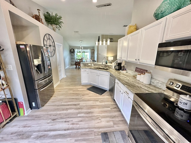 kitchen featuring stainless steel appliances, light stone countertops, kitchen peninsula, pendant lighting, and white cabinets