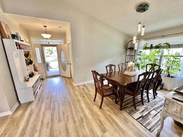 dining area with a textured ceiling and light wood-type flooring