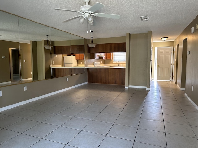 kitchen with pendant lighting, white appliances, sink, a textured ceiling, and kitchen peninsula