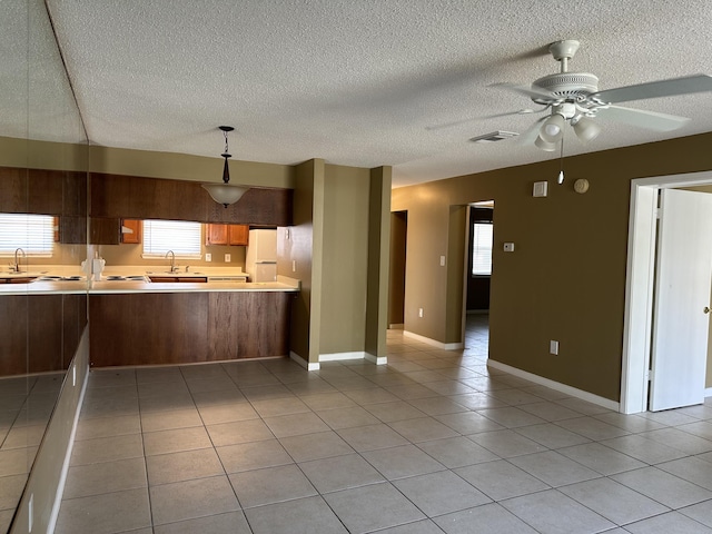 kitchen featuring ceiling fan, sink, pendant lighting, a textured ceiling, and light tile patterned floors