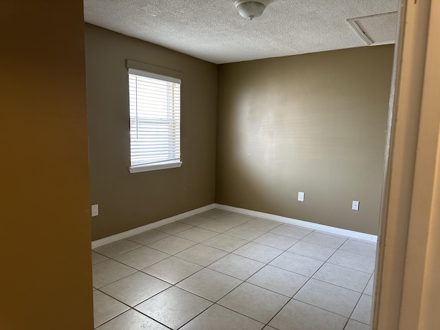 spare room featuring light tile patterned flooring and a textured ceiling