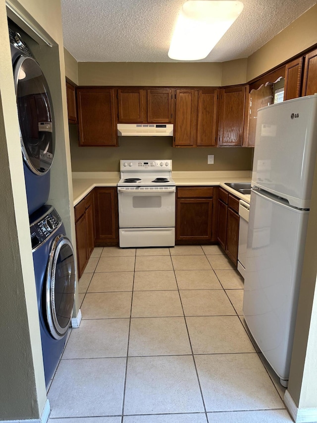 kitchen with white appliances, sink, light tile patterned floors, a textured ceiling, and stacked washer / drying machine