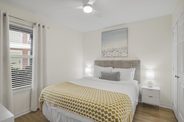 bedroom featuring a ceiling fan, a closet, baseboards, and wood finished floors