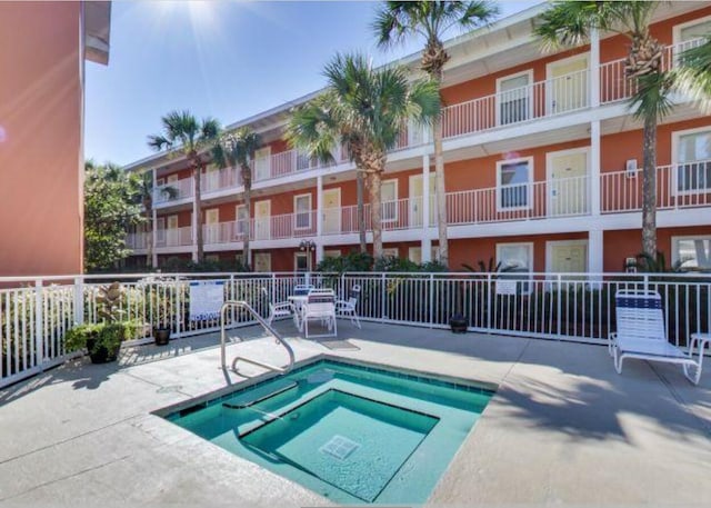 view of swimming pool with a patio, fence, and a hot tub