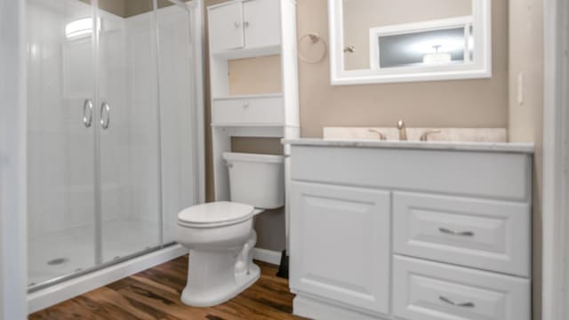 bathroom with toilet, a shower with door, wood-type flooring, and vanity