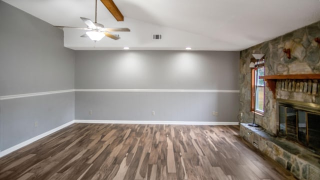 unfurnished living room with ceiling fan, dark hardwood / wood-style floors, a stone fireplace, and lofted ceiling with beams