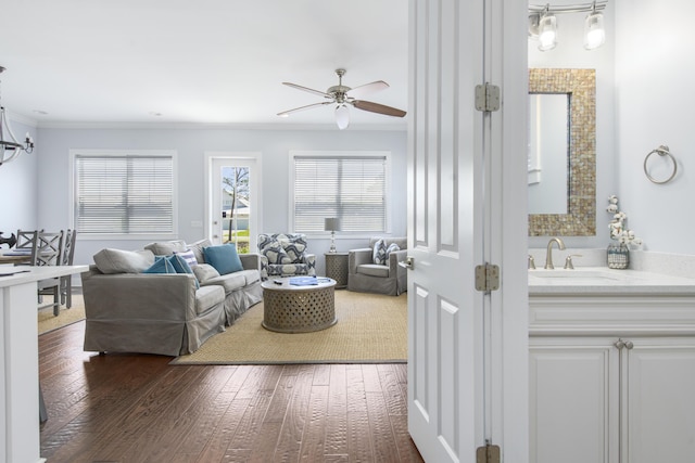 living room featuring dark hardwood / wood-style floors, ceiling fan, ornamental molding, and sink