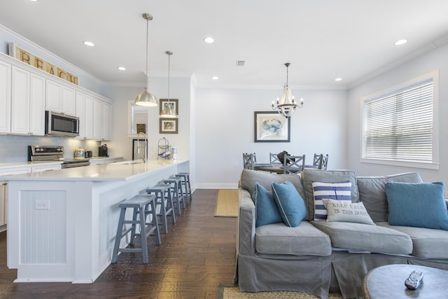 living room with sink, ornamental molding, dark hardwood / wood-style floors, and an inviting chandelier