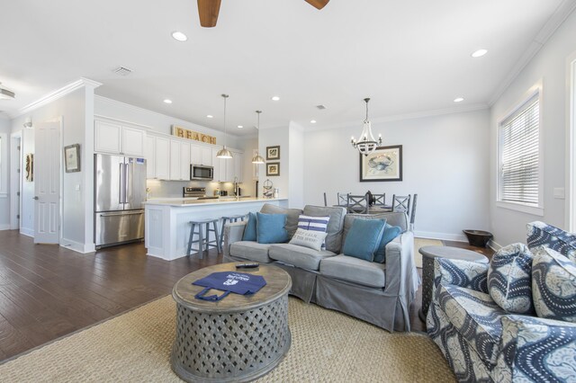 living room with ceiling fan with notable chandelier, ornamental molding, and dark wood-type flooring