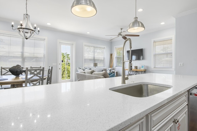 kitchen featuring decorative light fixtures, light stone counters, ornamental molding, and sink