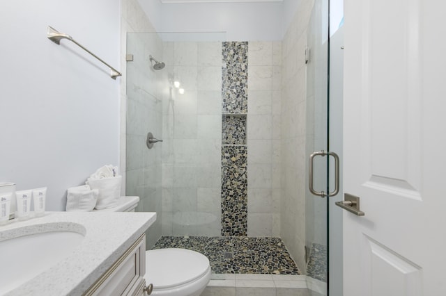 bathroom featuring tile patterned flooring, vanity, a shower with shower door, and toilet