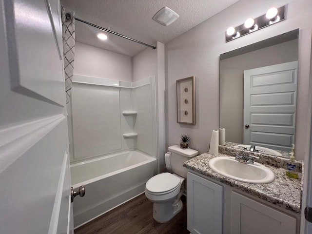 full bathroom with vanity, shower / washtub combination, hardwood / wood-style flooring, toilet, and a textured ceiling