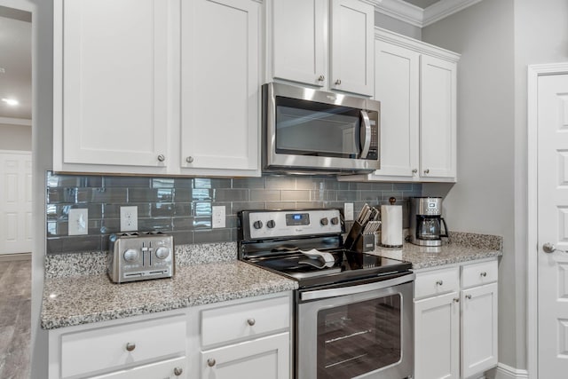 kitchen with stainless steel appliances, light stone counters, backsplash, white cabinets, and ornamental molding