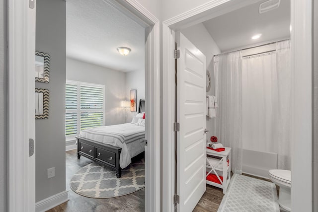 bathroom with a shower with shower curtain, hardwood / wood-style flooring, and toilet