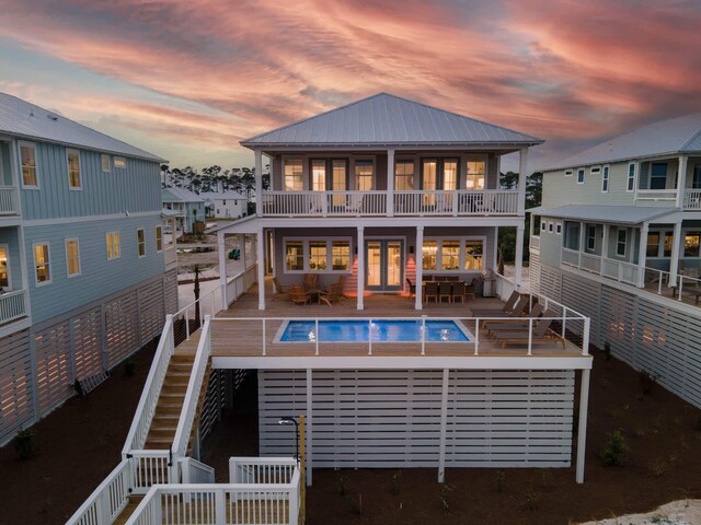 back house at dusk featuring a patio, a balcony, and a fenced in pool