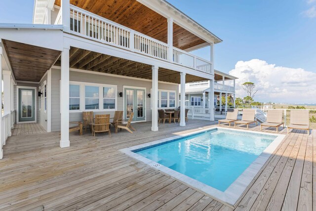 view of swimming pool featuring french doors and a deck