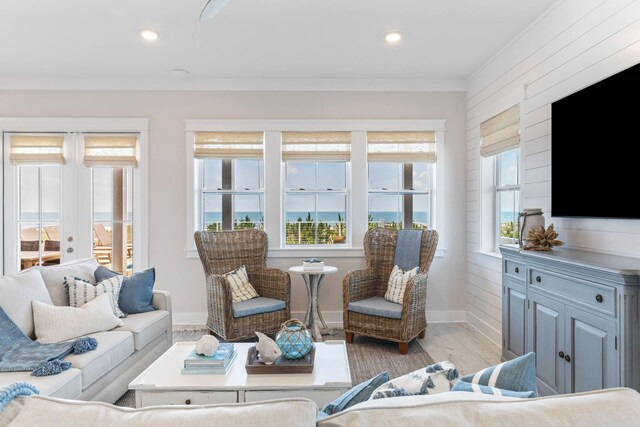 living room with light hardwood / wood-style floors, plenty of natural light, crown molding, and a water view