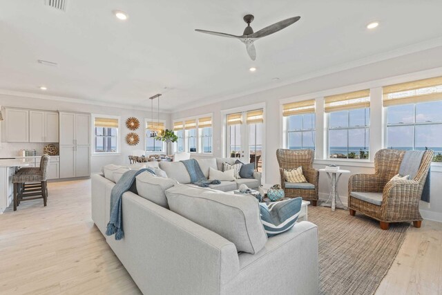 living room featuring ceiling fan, ornamental molding, and light hardwood / wood-style flooring