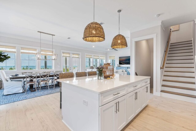 kitchen featuring pendant lighting, light hardwood / wood-style floors, a kitchen island, and white cabinetry