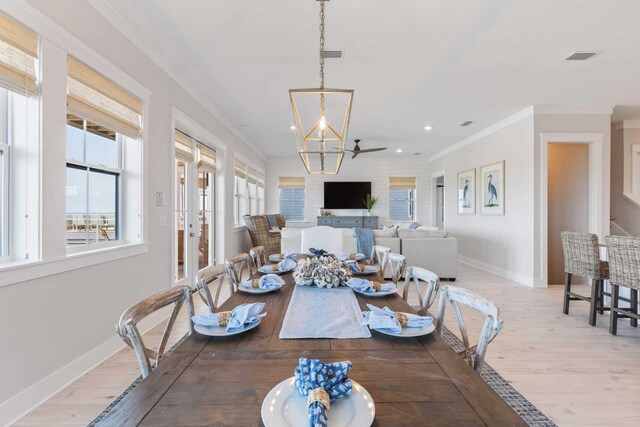 dining room with a healthy amount of sunlight, light hardwood / wood-style flooring, and ornamental molding