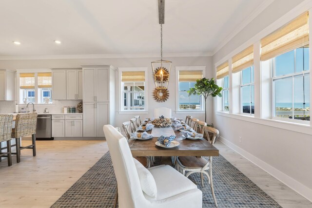 dining space featuring ornamental molding, light hardwood / wood-style floors, and a water view