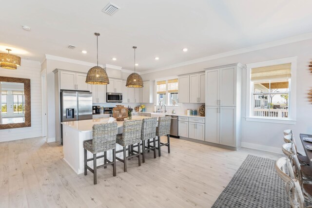 kitchen featuring a kitchen island, a wealth of natural light, light wood-type flooring, and appliances with stainless steel finishes