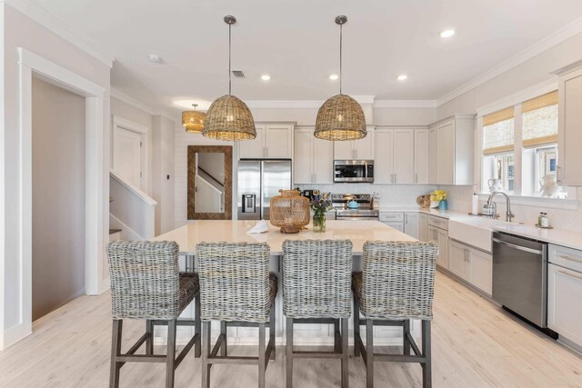 kitchen with tasteful backsplash, a center island, light wood-type flooring, appliances with stainless steel finishes, and sink