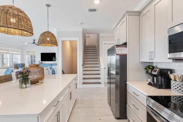 kitchen with light hardwood / wood-style floors, tasteful backsplash, pendant lighting, and stainless steel appliances