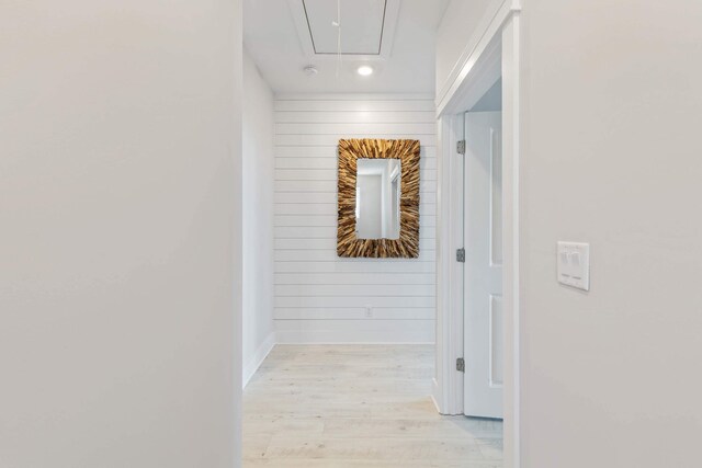 corridor with wooden walls and light hardwood / wood-style floors