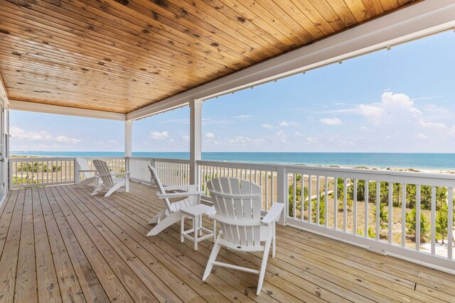 wooden deck featuring a beach view and a water view