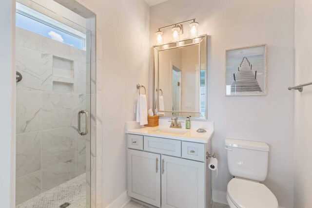 bathroom with a shower with shower door, vanity, and toilet