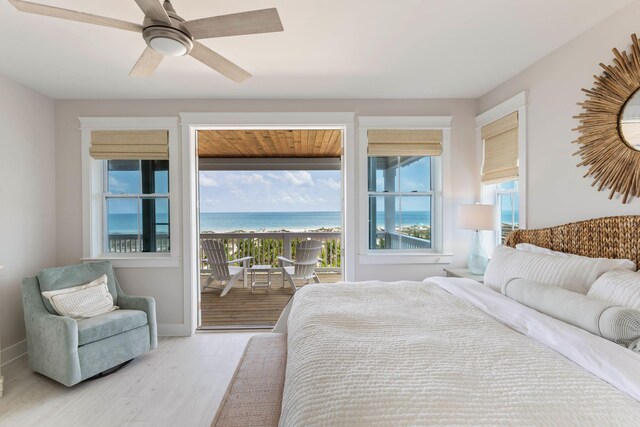 bedroom with access to outside, wood-type flooring, multiple windows, and a water view