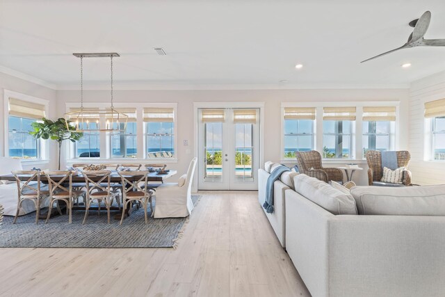 living room featuring crown molding, french doors, light wood-type flooring, and ceiling fan with notable chandelier