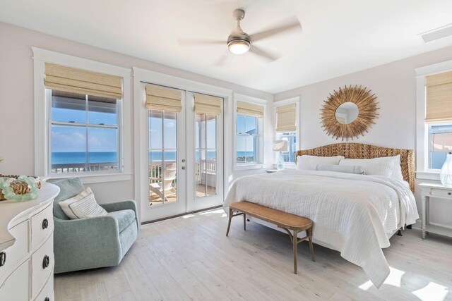 bedroom with ceiling fan, light hardwood / wood-style floors, french doors, a water view, and access to outside