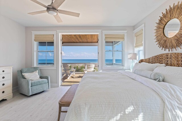 bedroom featuring ceiling fan, a water view, light hardwood / wood-style flooring, and access to outside