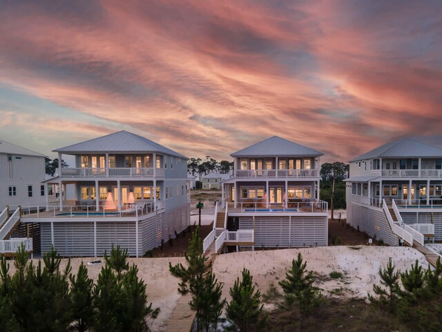 back house at dusk with a swimming pool and a balcony