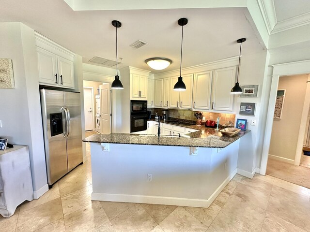 kitchen with black appliances, a breakfast bar, dark stone countertops, and kitchen peninsula