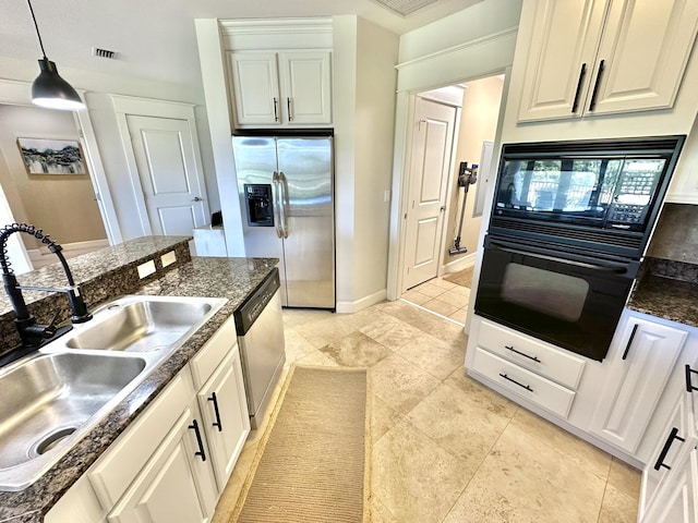 kitchen featuring sink, black appliances, dark stone countertops, white cabinetry, and hanging light fixtures