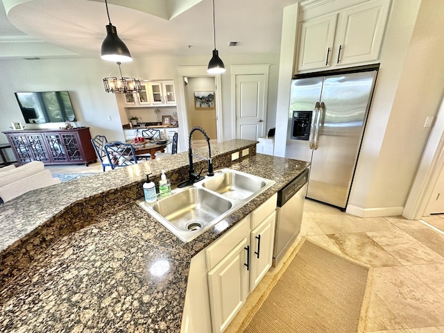 kitchen featuring appliances with stainless steel finishes, dark stone counters, sink, decorative light fixtures, and a notable chandelier