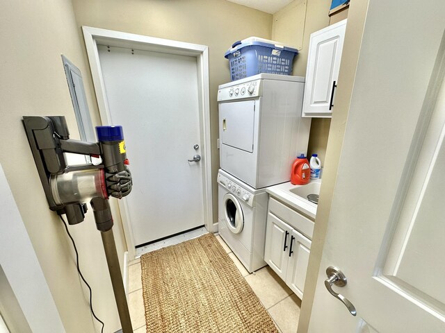 laundry area with cabinets, light tile patterned floors, and stacked washer and clothes dryer