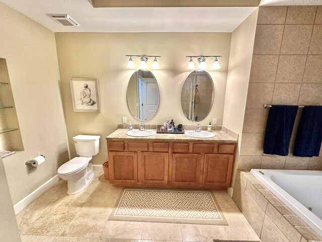 bathroom featuring tile patterned floors, vanity, tiled bath, and toilet