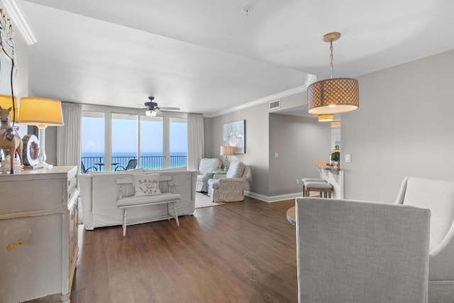 living room featuring dark hardwood / wood-style flooring, ceiling fan, a water view, and crown molding